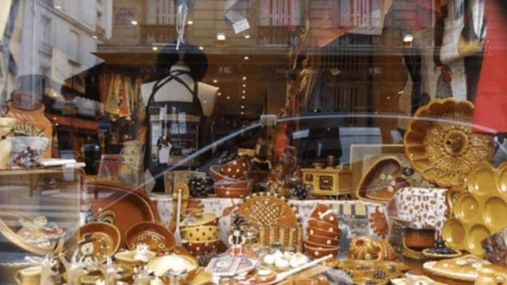 Colorful ceramics displayed in a Parisian shop window, showcasing plates, bowls, and decorative items.