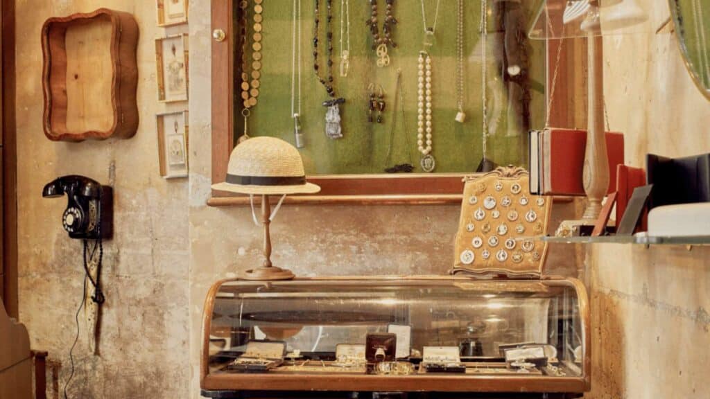 Vintage Parisian boutique with jewelry display, straw hat, and antique telephone, showcasing rustic charm.