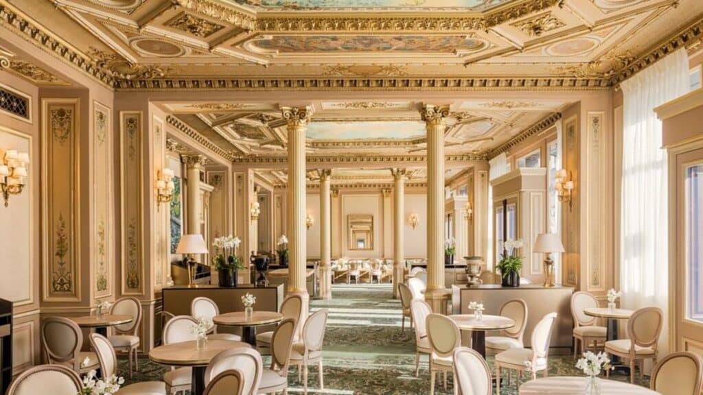 Luxurious Parisian cafe with ornate moldings, tall columns, and elegant seating in a classic Belle Époque style.