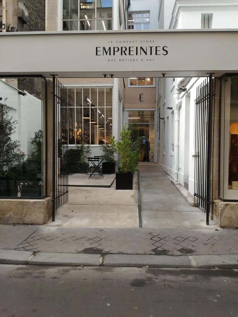 Entrance to EMPREINTES art concept store in Paris, featuring outdoor seating and plants.