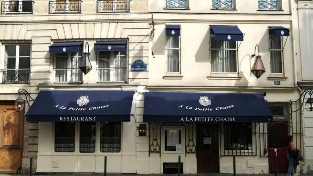 Facade of La Petite Chaise restaurant with blue awnings in Paris. Historic building with classic Parisian architecture.