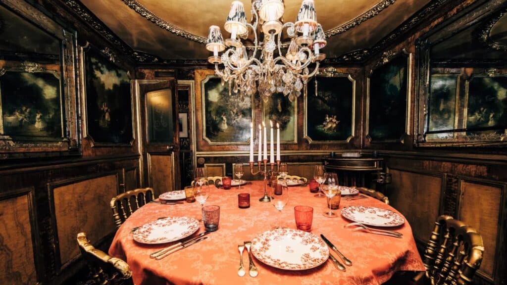Opulent dining room with chandelier, ornate wood paneling, and elegantly set table in Parisian style.