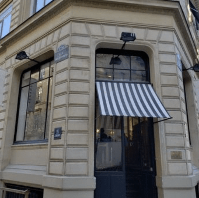 Classic Parisian corner cafe with striped awning in the 7th arrondissement.