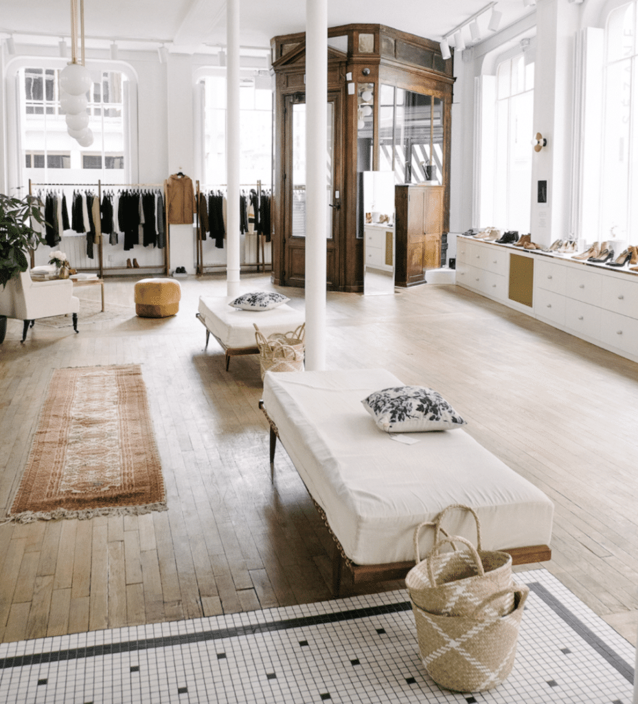 Spacious luxury boutique with parquet floors, white walls, and elegant wooden fitting room in Paris.