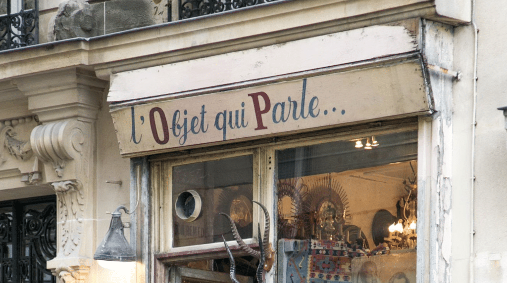 Exterior of a vintage shop in Paris with antique decorations and ornate Haussmannian facade.
