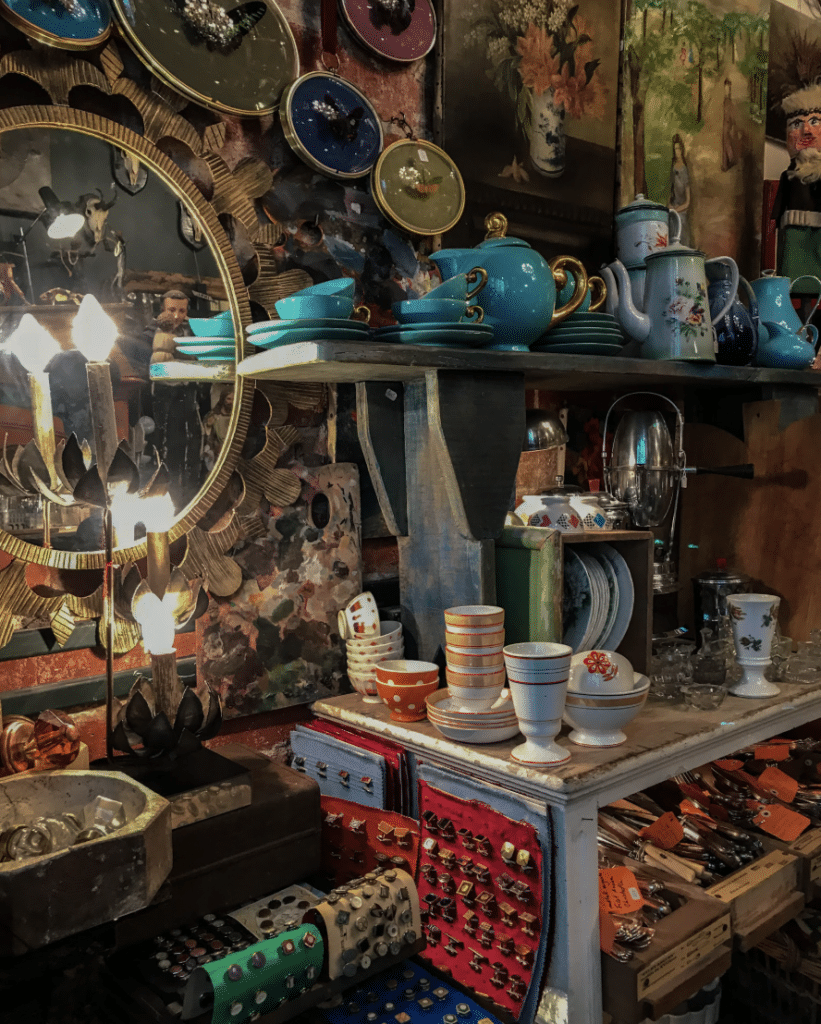 Charming Paris antique shop with vintage dishes, ornate mirror, and eclectic decor items.