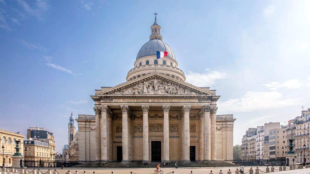 Panthéon in Paris, Neoclassical architecture with French flag, spacious square, clear blue sky.