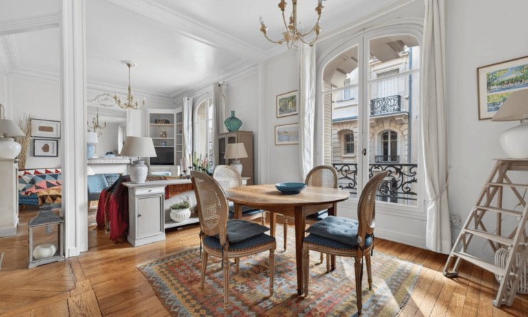 Parisian dining room with parquet floors, arched windows, high ceilings, and classic moldings in a Haussmann building.